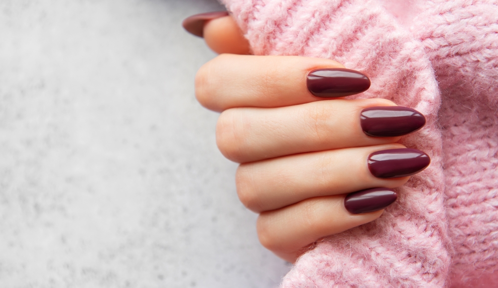 a,close up,of,a,woman's,hand,showcasing,deep,burgundy,almond shaped