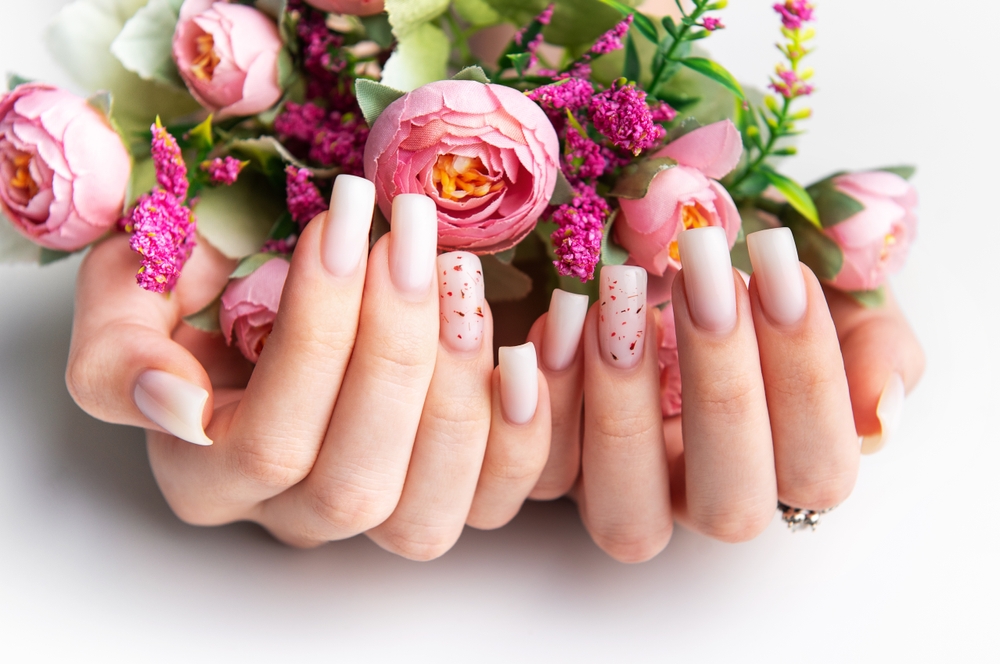 woman,showcasing,her,modern,pink,manicure,while,holding,a,bouquet