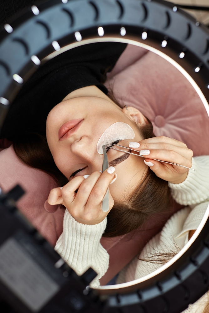 professional,beautician,with,tweezers,makes,eyelash,extension,for,beautiful,woman